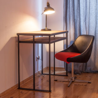 Schreibtisch aus Holz mit Lampe und Sessel